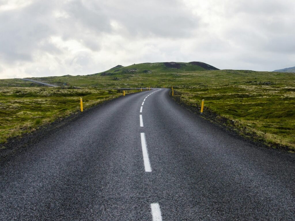 Empty road stretches through lush countryside under cloudy skies, ideal for travel themes.