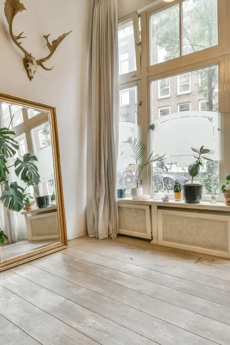 Salon intérieur lumineux avec miroir doré et plantes vertes